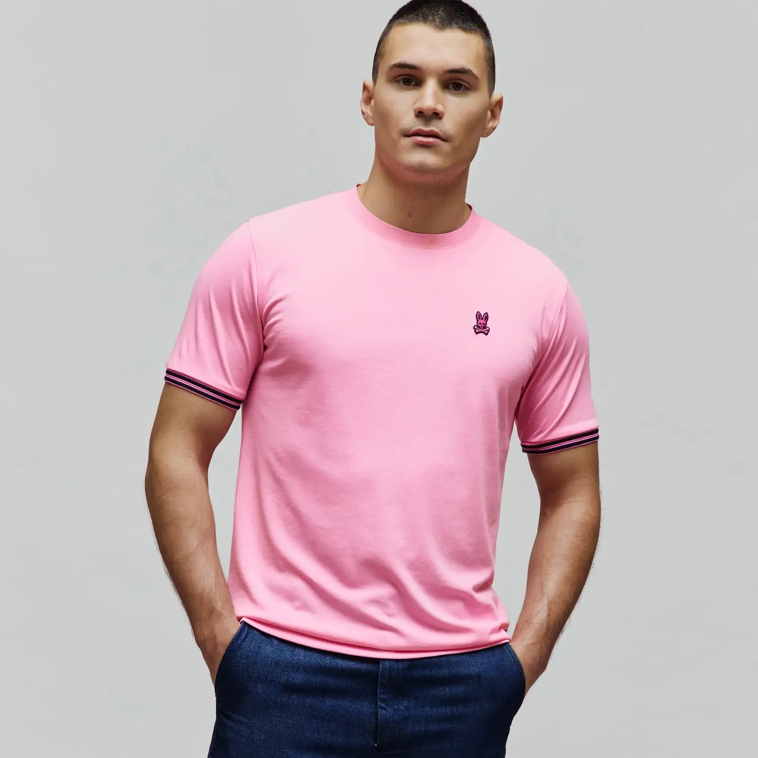 Mens Clark Performance Tee in bright pink, featuring a classic fit, smooth jersey knit, small fuchsia embroidered Psycho Bunny skull logo on the left chest, and navy and pink striped sleeve cuffs. (3)