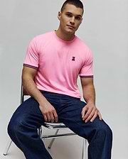 Mens Clark Performance Tee, a classic fit pink jersey knit t-shirt with an embroidered pink and black Psycho Bunny skull logo on the left chest and striped dark blue and pink ribbed cuffs. (1)