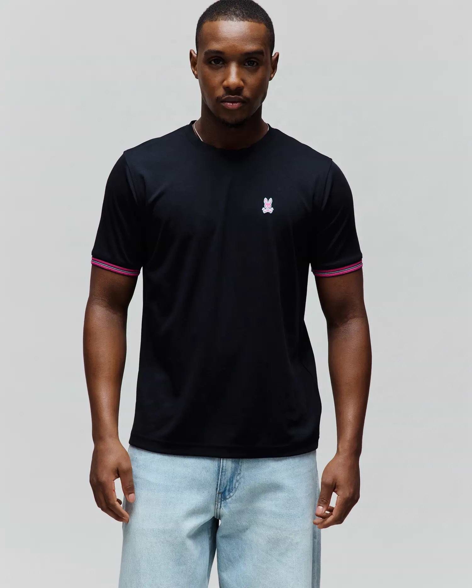 Mens Clark Performance Tee, a black classic fit smooth jersey t-shirt with a small embroidered pink and white Psycho Bunny skull logo on the left chest and ribbed sleeve cuffs featuring pink and white stripes.