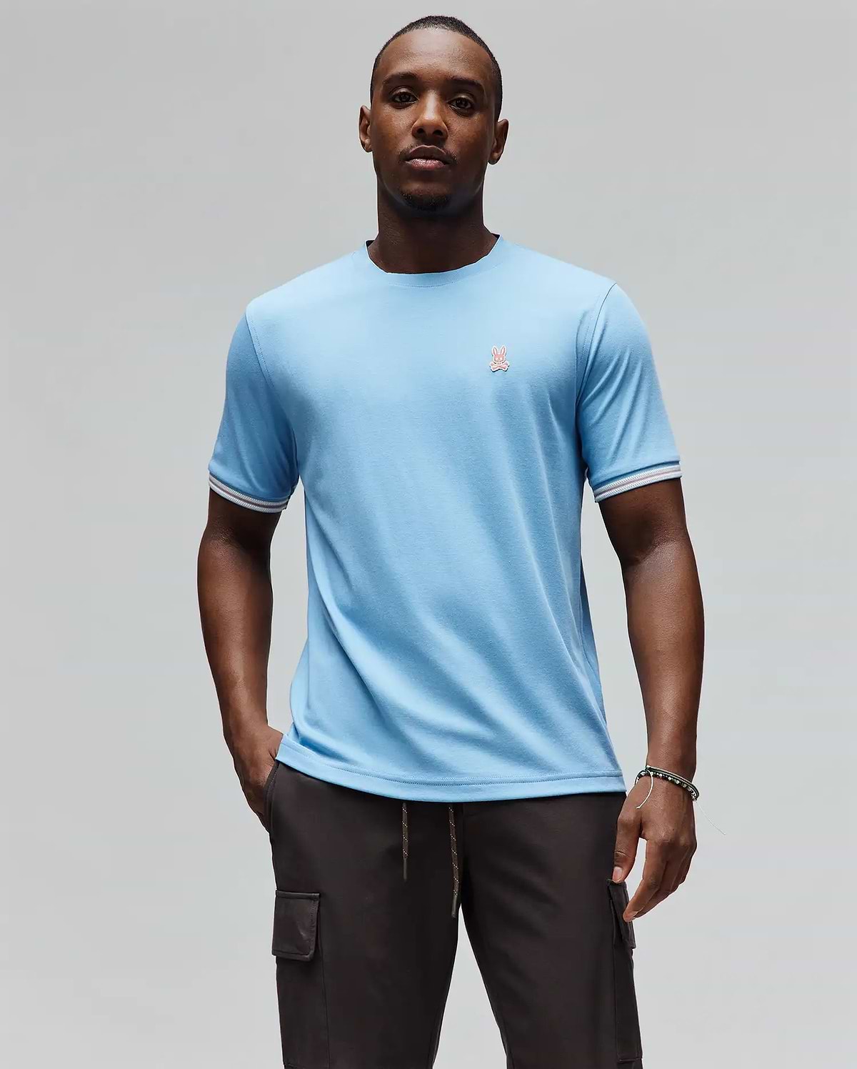 Mens Clark Performance Tee, a sky blue classic fit jersey knit t-shirt featuring a small embroidered pink Psycho Bunny skull logo on the left chest and white and red striped ribbed sleeve cuffs. (1)