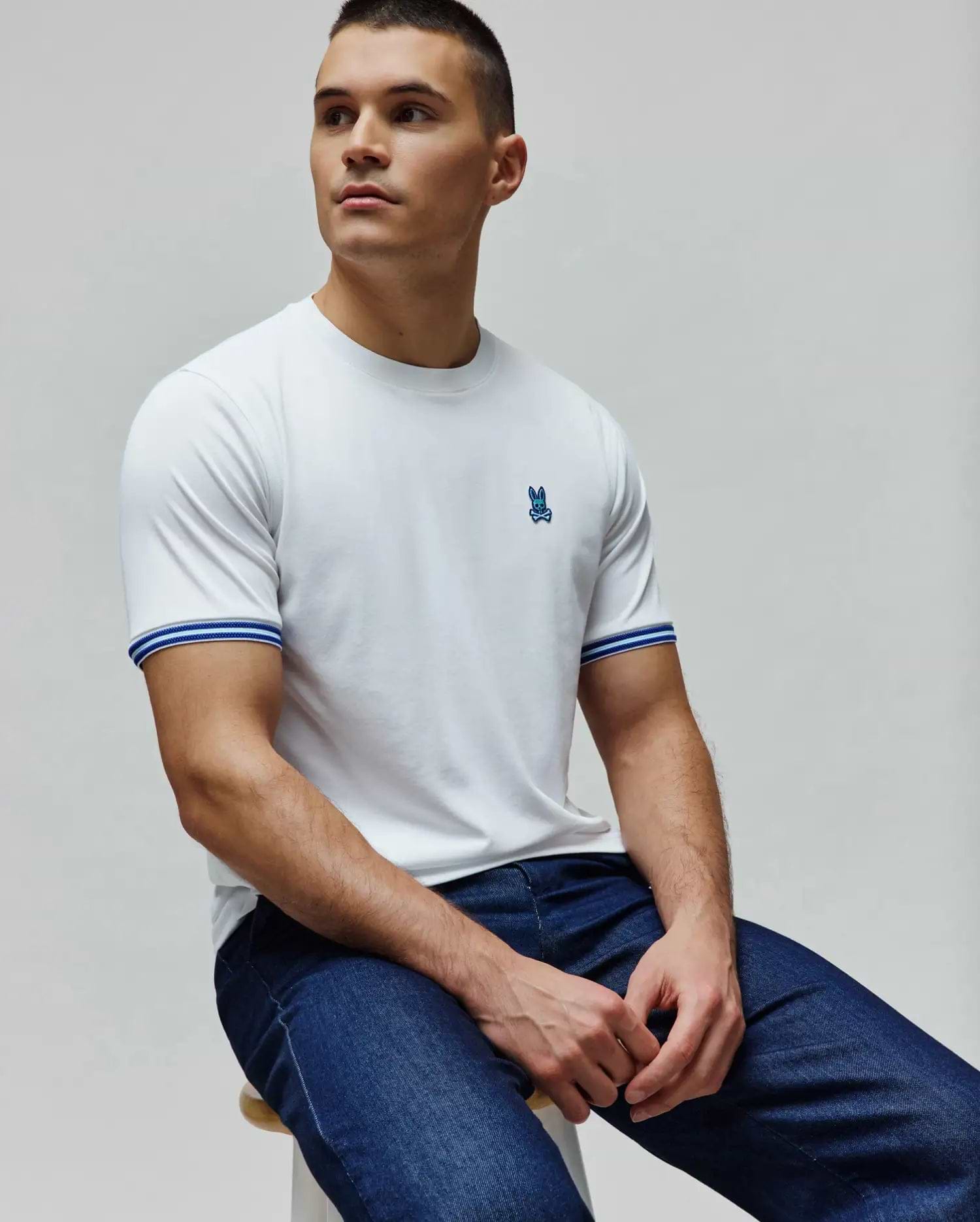Mens Clark Performance Tee, a white classic fit smooth jersey t-shirt with a small embroidered blue Psycho Bunny skull logo on the left chest and blue and white striped ribbed cuffs. (1)