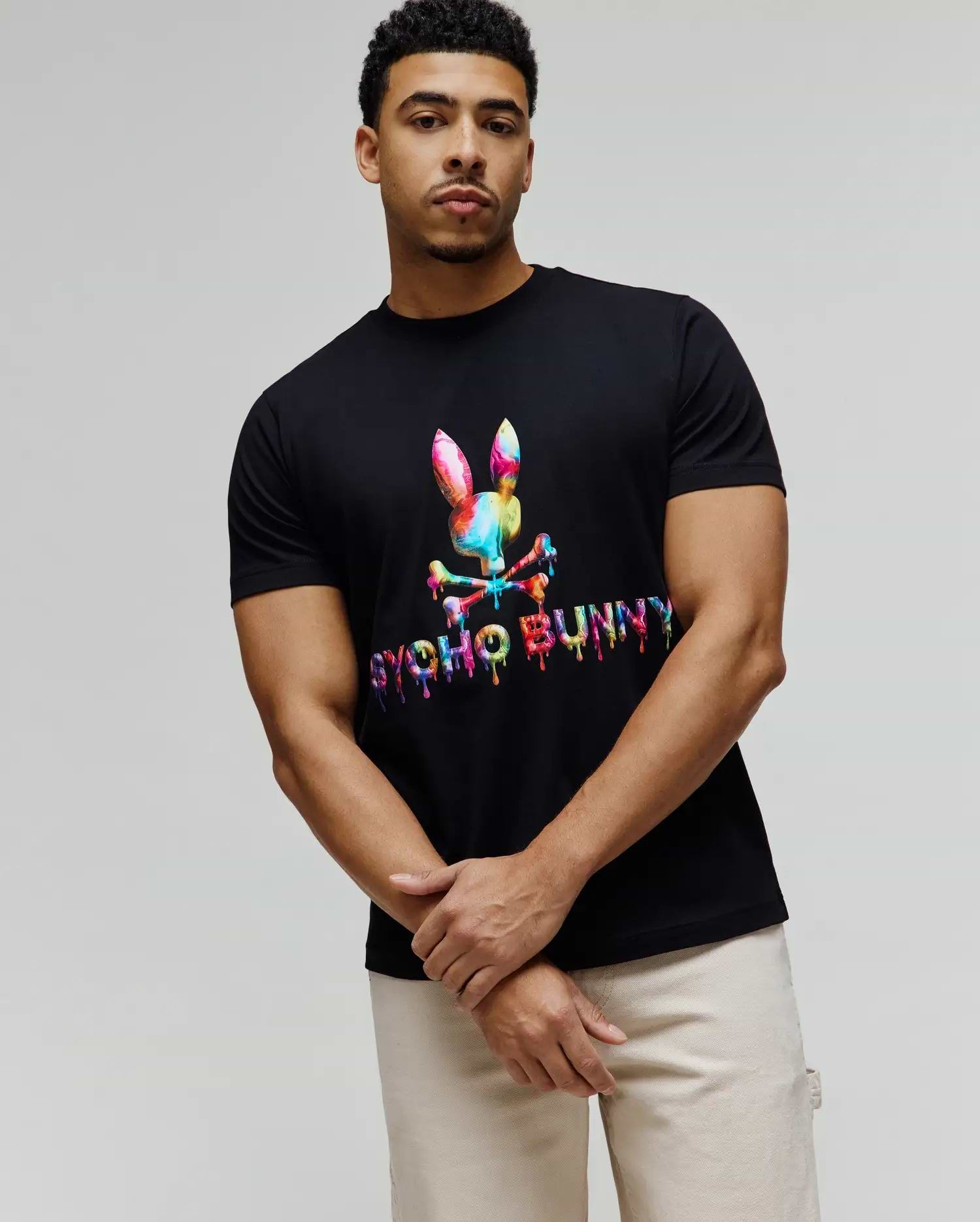 Mens Wells Graphic Tee in black, featuring a large, vibrant rainbow dripping Psycho Bunny skull logo and text on the chest, classic fit jersey knit. (1)