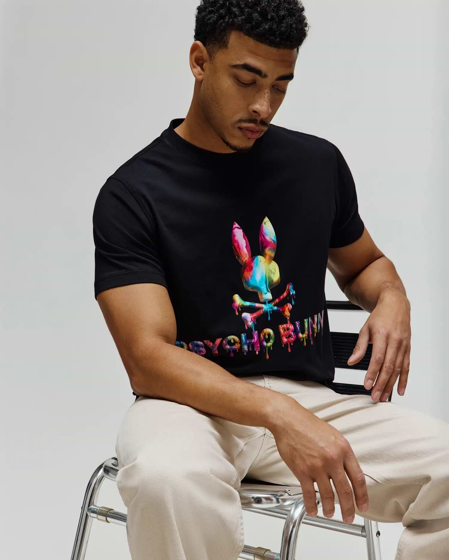 Mens Wells Graphic Tee, a black classic fit jersey t-shirt featuring a large, vibrant multicolor drip-effect Psycho Bunny skull logo and matching text on the center chest. (3)