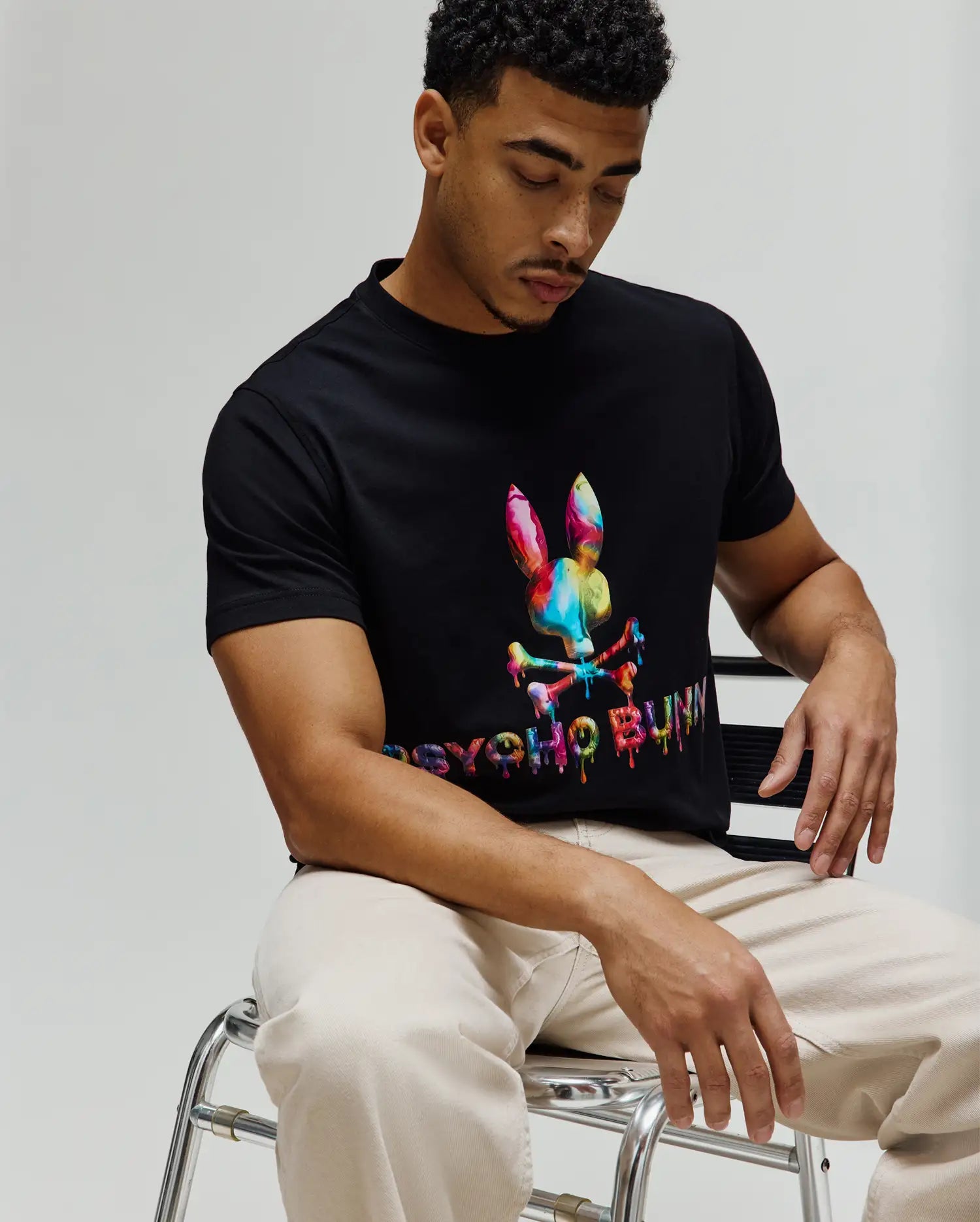 Mens Wells Graphic Tee, a black classic fit jersey t-shirt featuring a large, vibrant multicolor drip-effect Psycho Bunny skull logo and matching text on the center chest. (3)