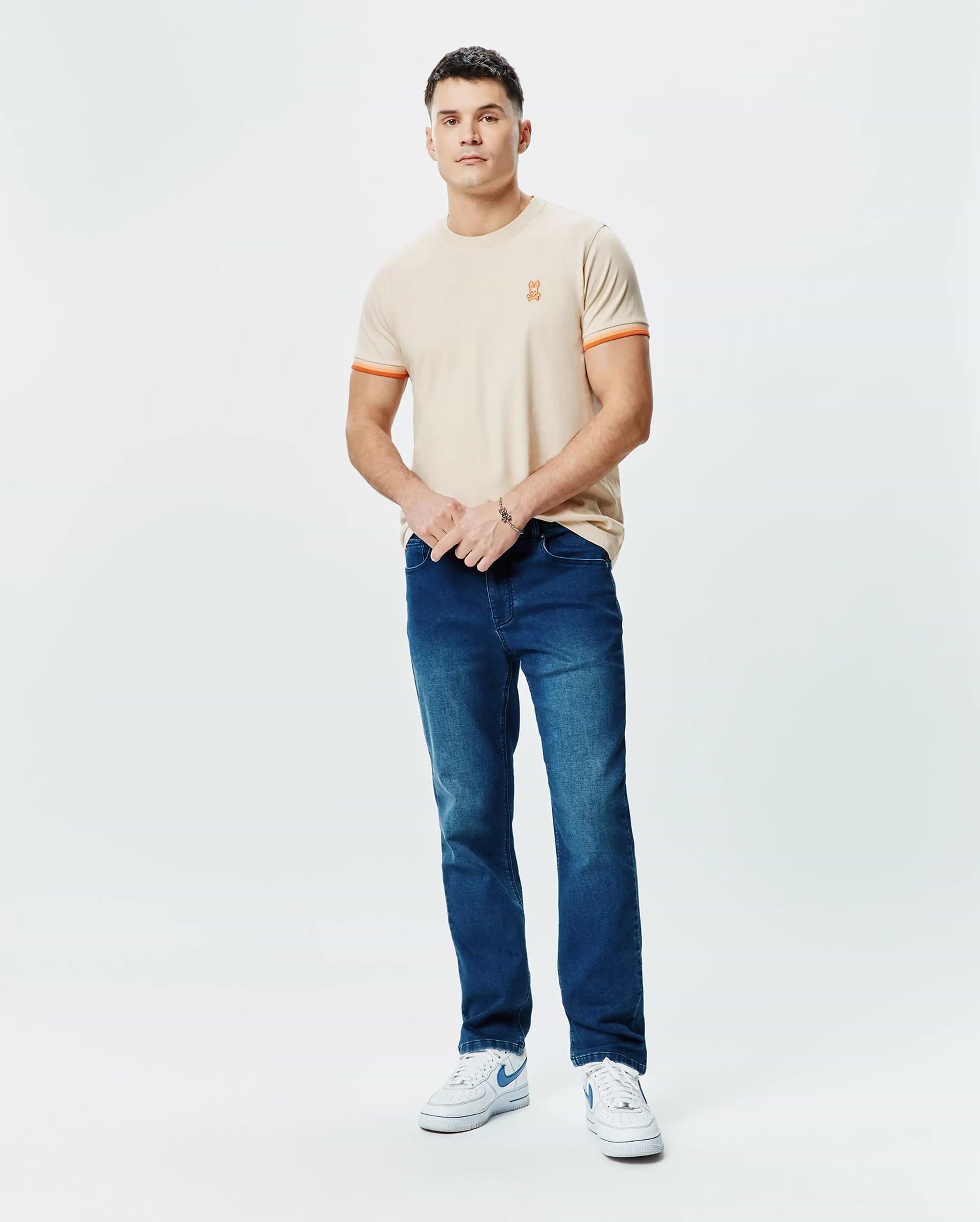 Mens Holden Tee, a classic fit beige jersey t-shirt featuring a small orange embroidered Psycho Bunny skull logo on the left chest and orange striped cuffs. (4)
