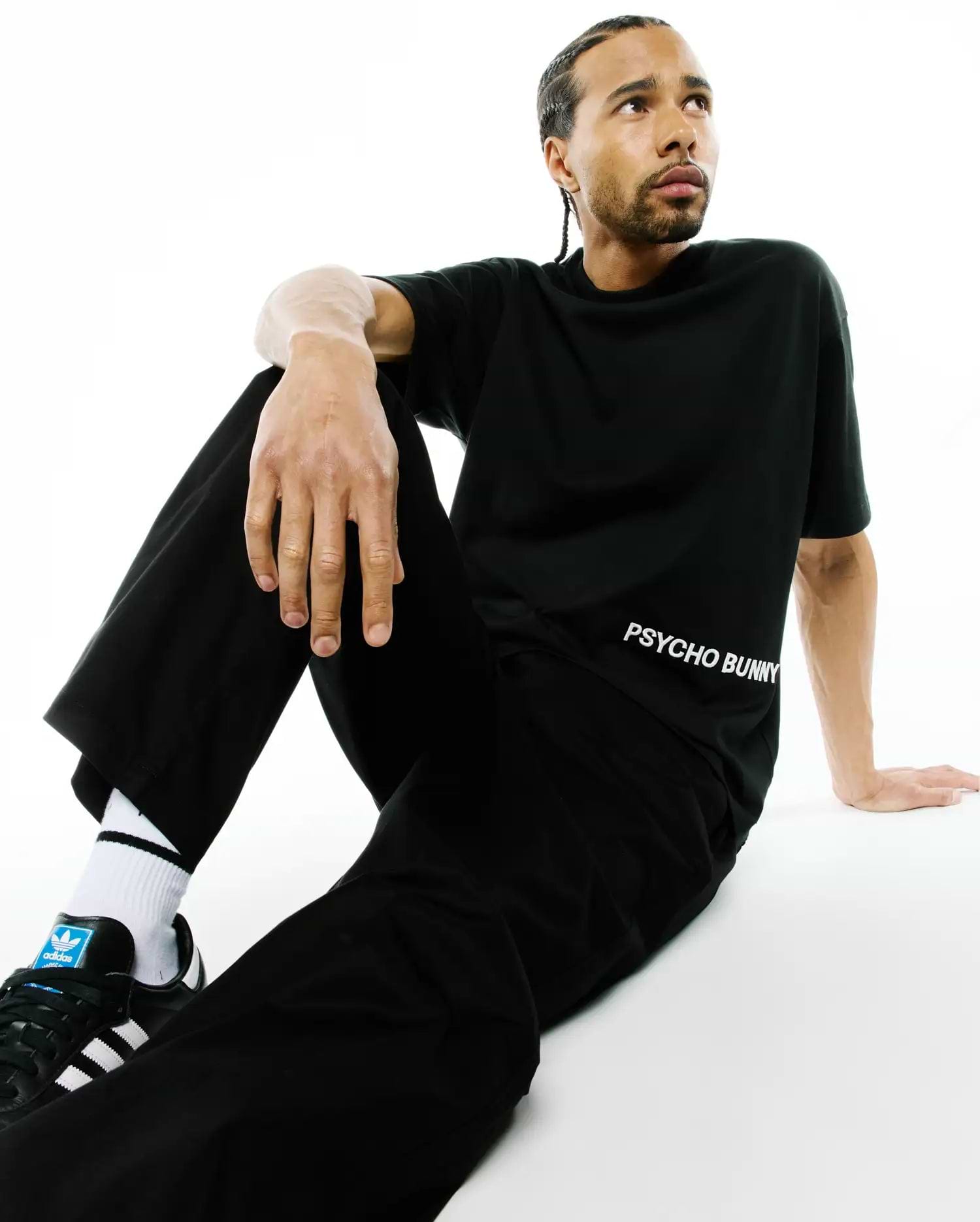Mens Haiden Relaxed Heavy Weight Tee in black, featuring a relaxed fit and smooth heavy jersey fabric. The white Psycho Bunny text logo is prominently placed on the lower left torso.