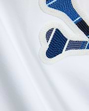 Mens Drew Embroidered Graphic Tee, white jersey knit, featuring a large Psycho Bunny graphic with blue, dark blue, and grey plaid-like embroidery outlined in white.