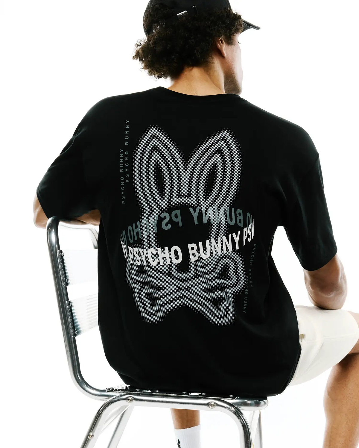 Mens Alex Relaxed Back Graphic Tee in black jersey knit, featuring a large white and grey dotted Psycho Bunny skull graphic on the back and vertical Psycho Bunny text along the shoulders. (1)