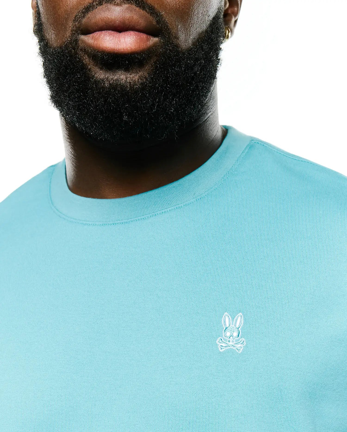 Men's Norman Longsleeve Oversized Tee in aqua blue, featuring a soft jersey knit fabric, ribbed crewneck, and a small white embroidered Psycho Bunny skull logo on the left chest. (2)