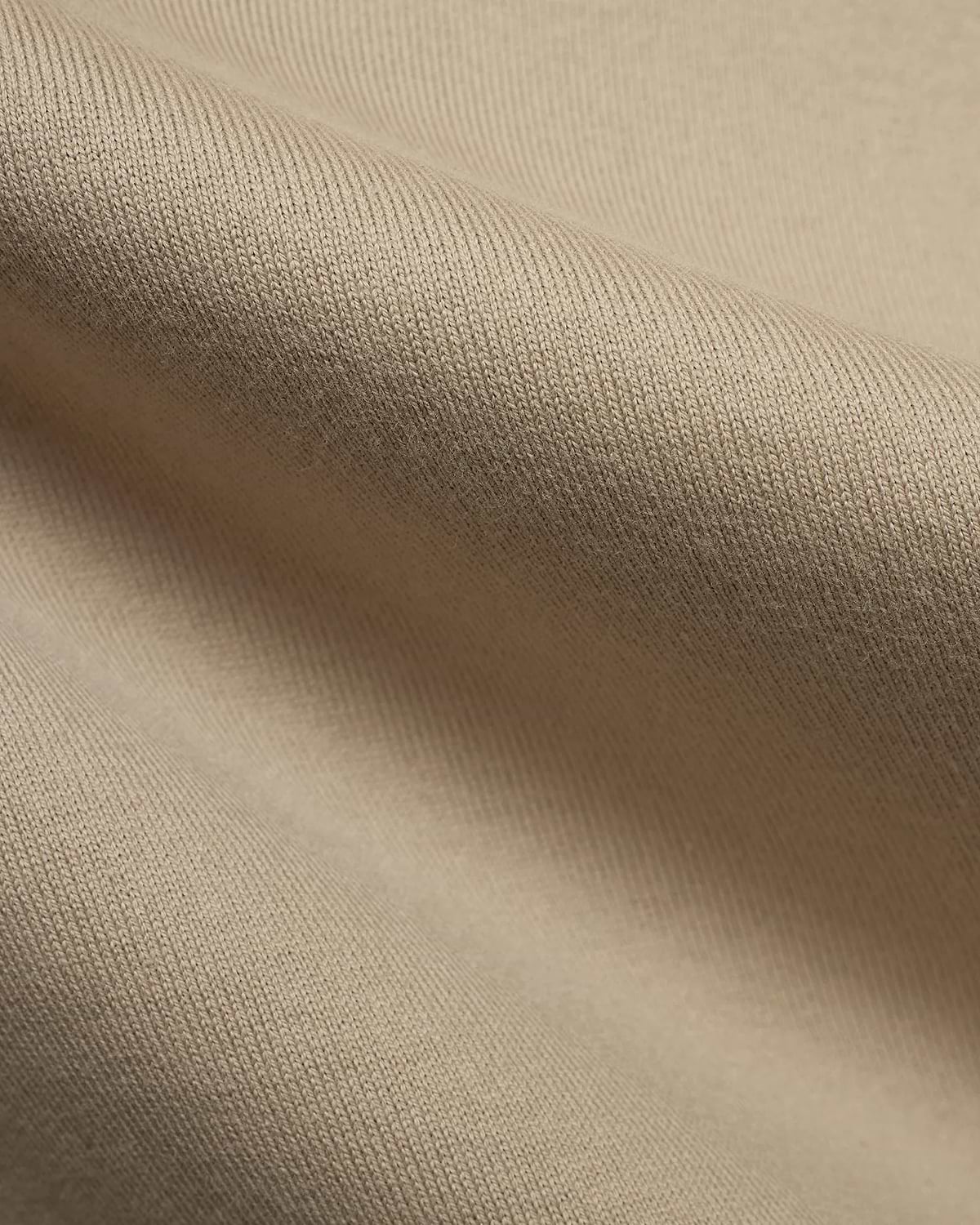 Mens Norman Long Sleeve Relaxed Fit Tee, crafted from a premium, soft beige jersey knit fabric, showcasing its refined texture and comfortable drape in a close-up detail.