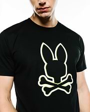 Mens Bruno Graphic Tee, a black classic fit jersey t-shirt featuring a prominent white outline Psycho Bunny skull logo with vibrant neon yellow stitching detail on the chest.