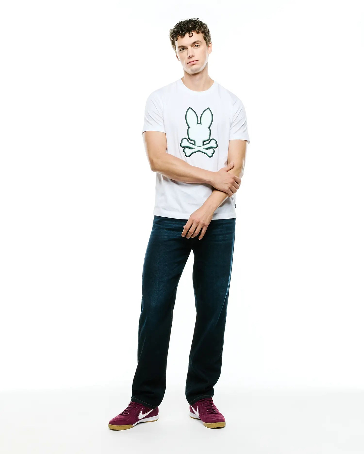 Mens Bruno Graphic Tee, a classic fit white jersey t-shirt featuring a prominent, centered green outline Psycho Bunny skull and crossbones logo graphic on the chest.
