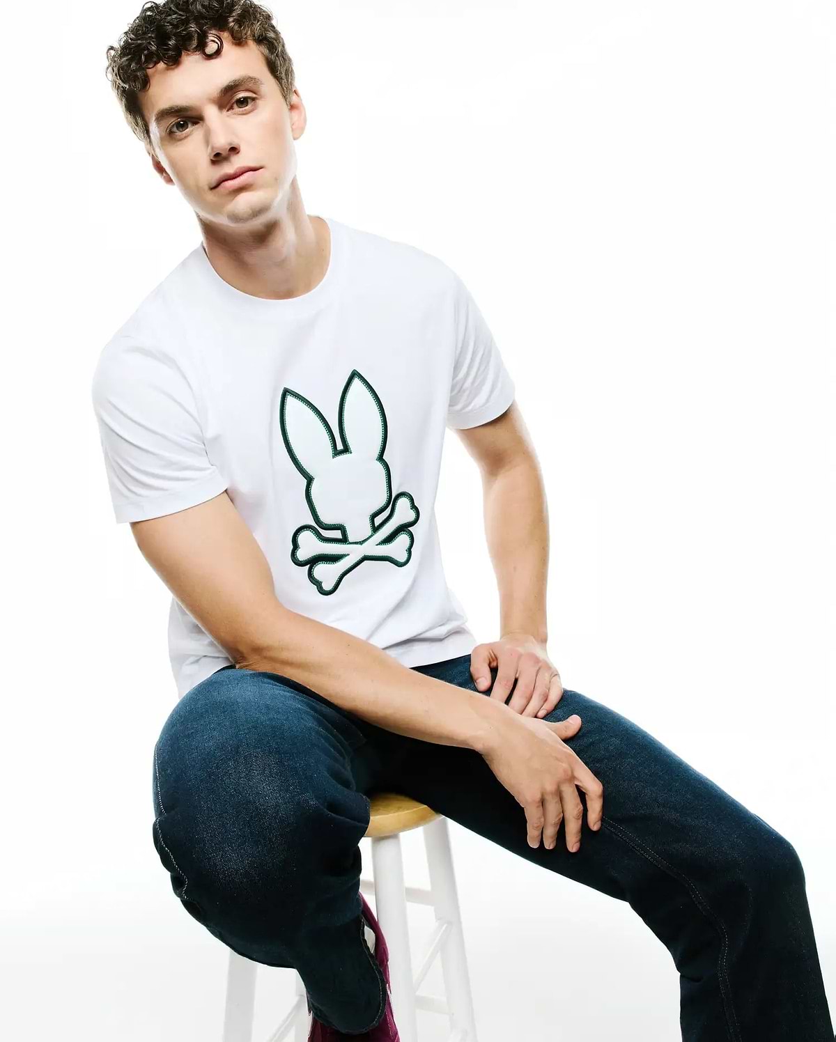 Mens Bruno Graphic Tee, white classic fit jersey t-shirt featuring a large, centered green-outlined Psycho Bunny skull and crossbones graphic logo.