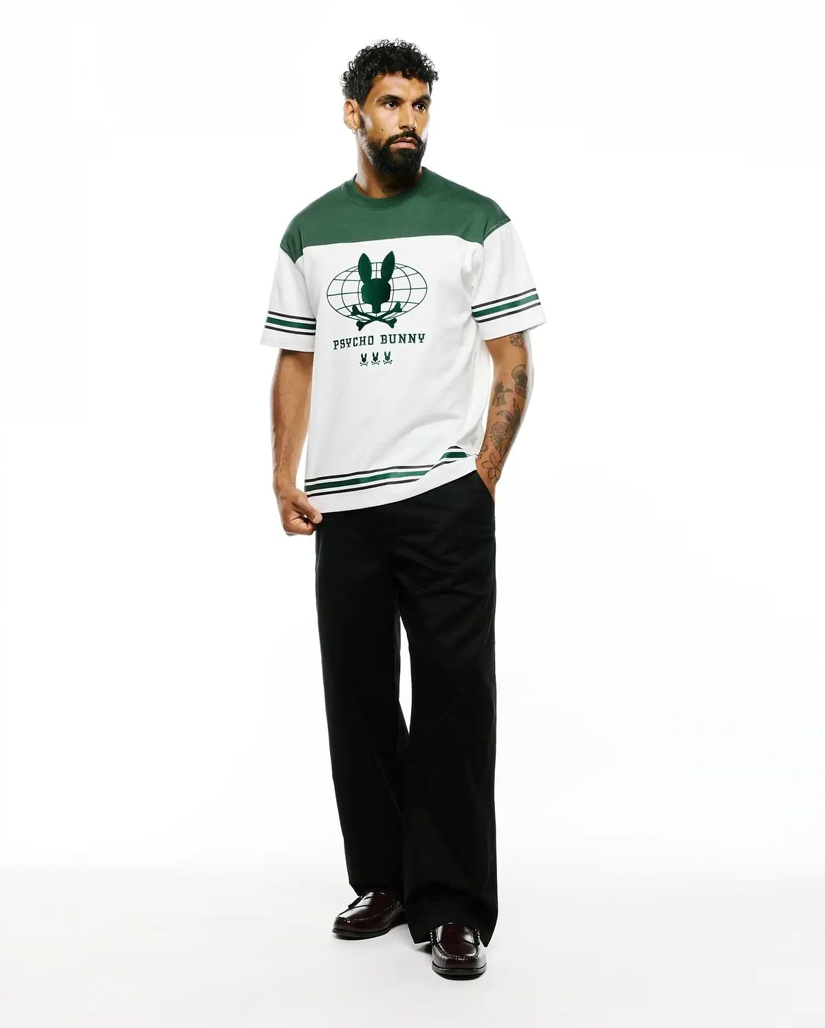 Mens Mike Graphic Jersey Tee, a white and green color block jersey t-shirt with a large central green Psycho Bunny skull and globe graphic, featuring striped sleeves and a classic fit. (5)