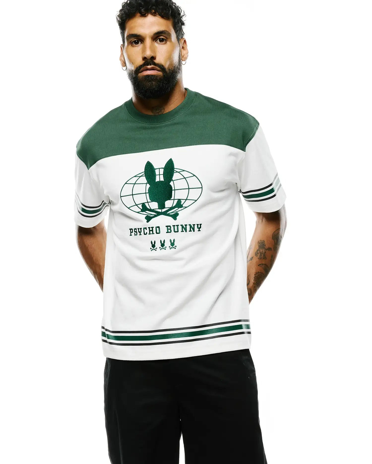 Mens Mike Graphic Jersey Tee, a relaxed fit white jersey tee featuring green color-block shoulders, a large green global bunny skull logo with Psycho Bunny text and three smaller bunny skulls on the chest, finished with green and black striped cuffs and hem. (4)