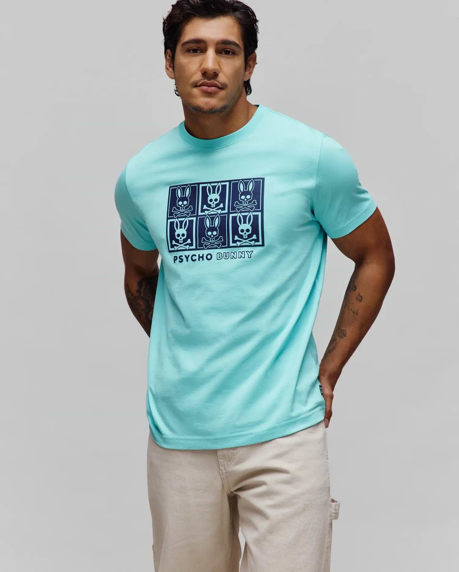 Mens Keon Graphic Tee, a classic fit aqua jersey t-shirt with a large dark blue center chest graphic print featuring six Psycho Bunny skull logos in a grid above PSYCHO BUNNY text.