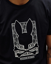 Black classic fit jersey Mens Keon Embroidered Graphic Tee with a large central white embroidered Psycho Bunny skull graphic, featuring a repeating bunny skull and crossbones pattern and PSYCHO BUNNY text. (2)