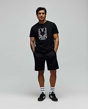 Mens Keon Embroidered Graphic Tee. Black classic-fit jersey t-shirt with a large white embroidered Psycho Bunny skull logo graphic and text on the chest, complemented by black relaxed shorts. (3)