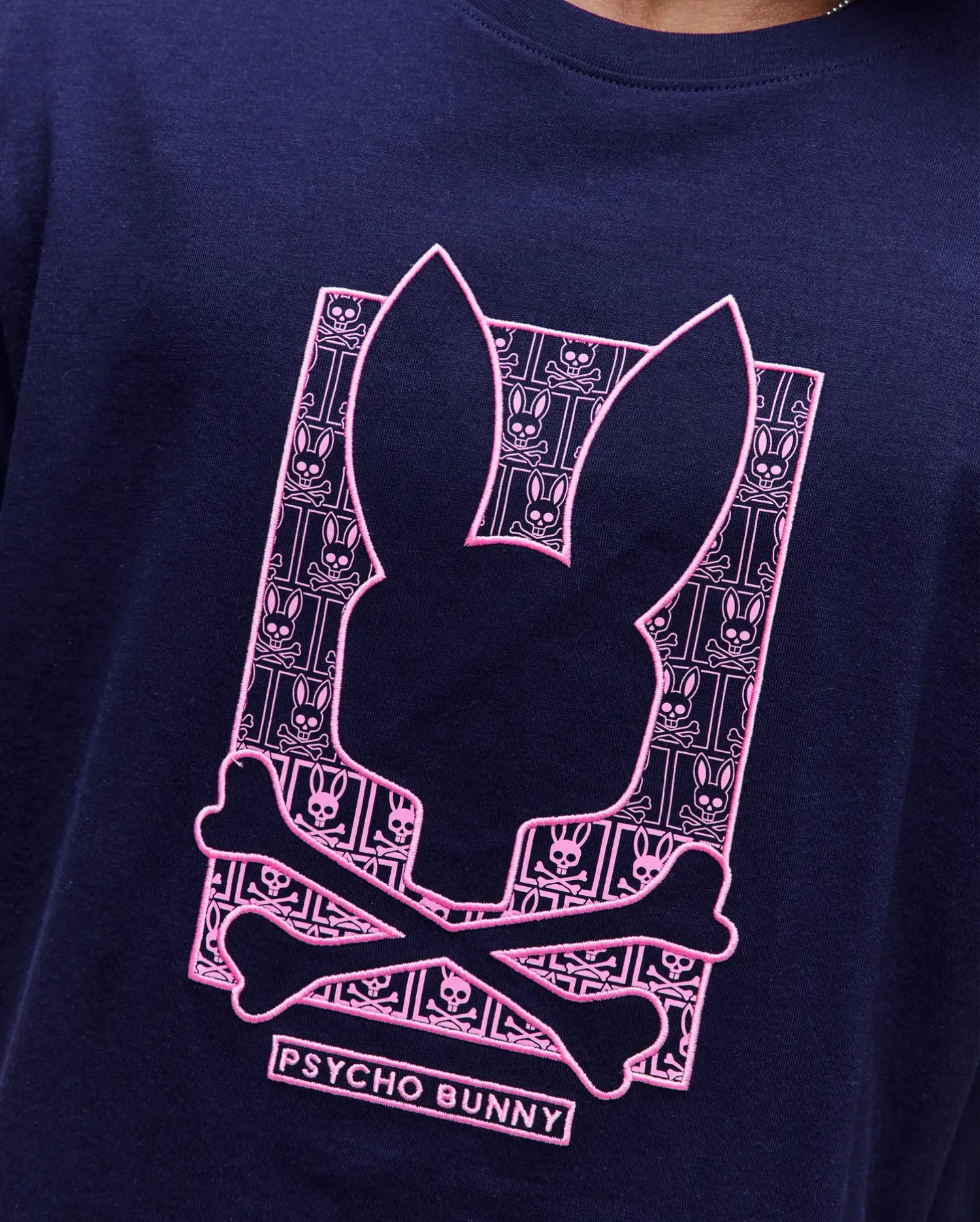 Navy classic fit jersey T-shirt with a large, central pink embroidered Psycho Bunny skull logo graphic, filled with a repeating mini bunny skull and crossbones pattern. Mens Keon Embroidered Graphic Tee. (3)