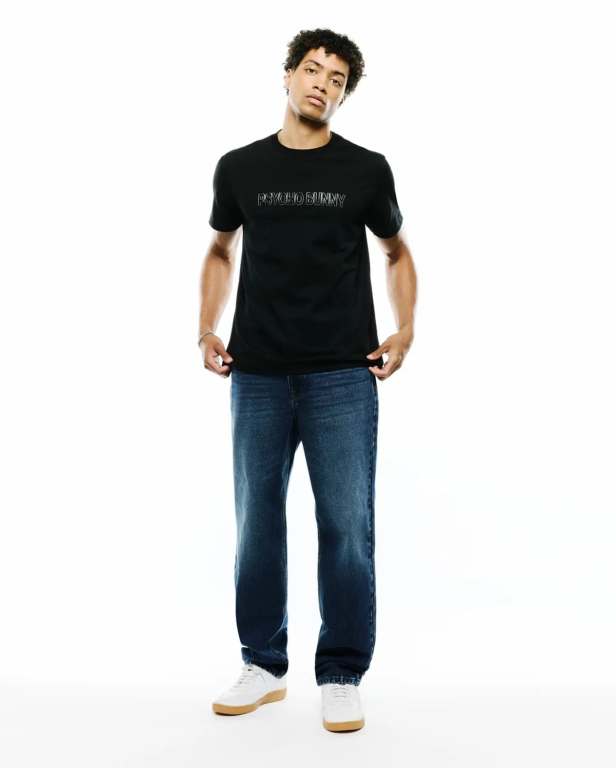 Mens Joji Wordmark Graphic Tee, a black premium classic fit jersey t-shirt featuring a white outline PSYCHO BUNNY wordmark graphic prominently centered on the chest.