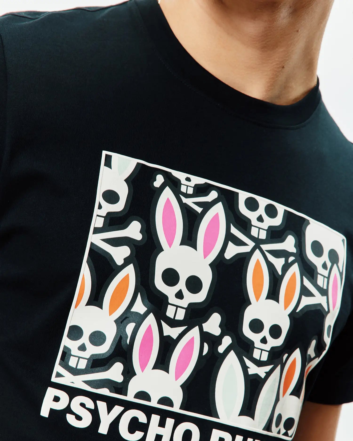 Mens Byron Graphic Tee, black jersey knit, classic fit, with a large chest graphic of white bunny skulls, pink, orange, and light blue ears, crossbones, and PSYCHO BUNNY text. (3)