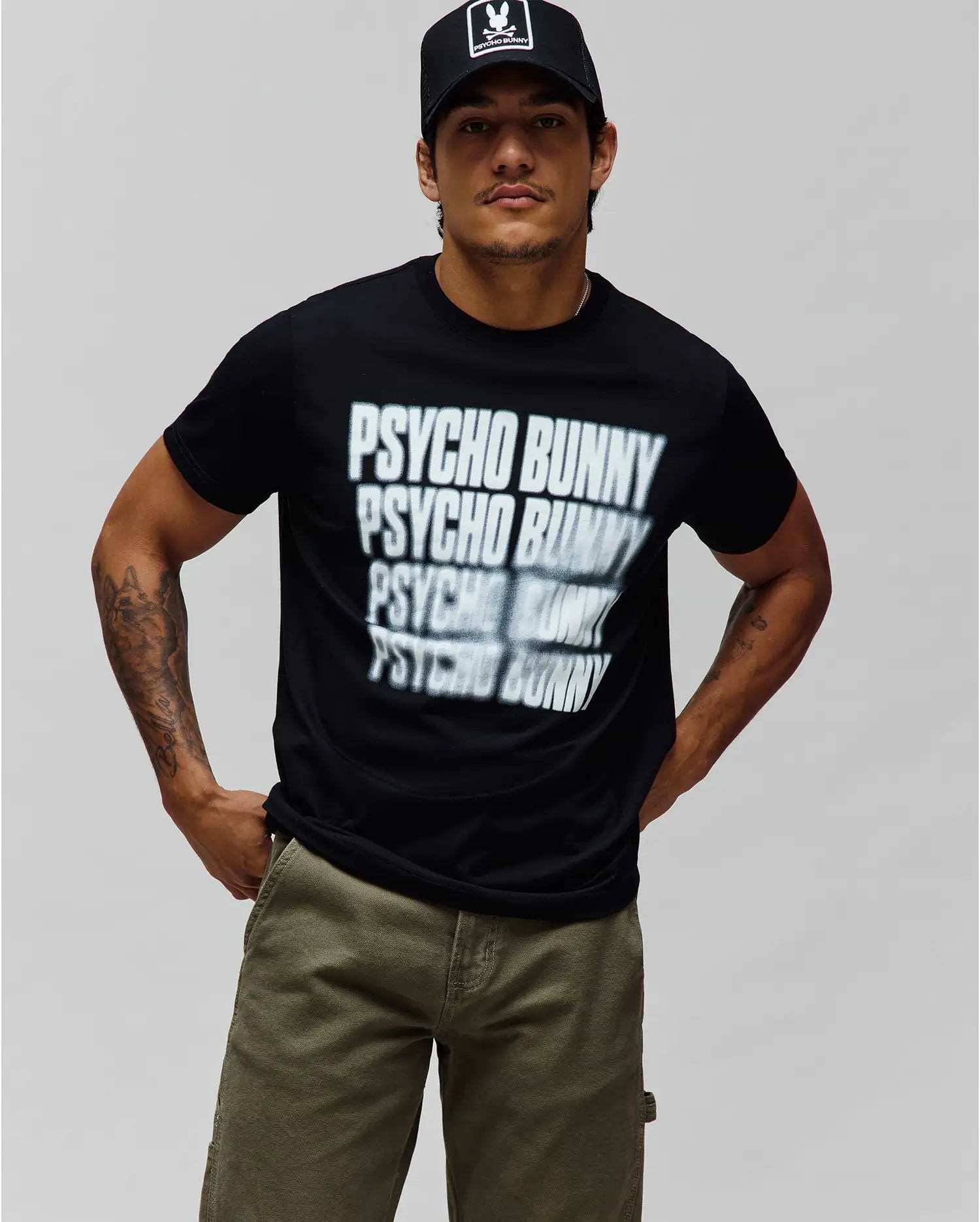 Mens Lawrence Graphic Tee, black classic fit jersey t-shirt with a large white and grey fading repeated PSYCHO BUNNY text graphic on the chest. (2)