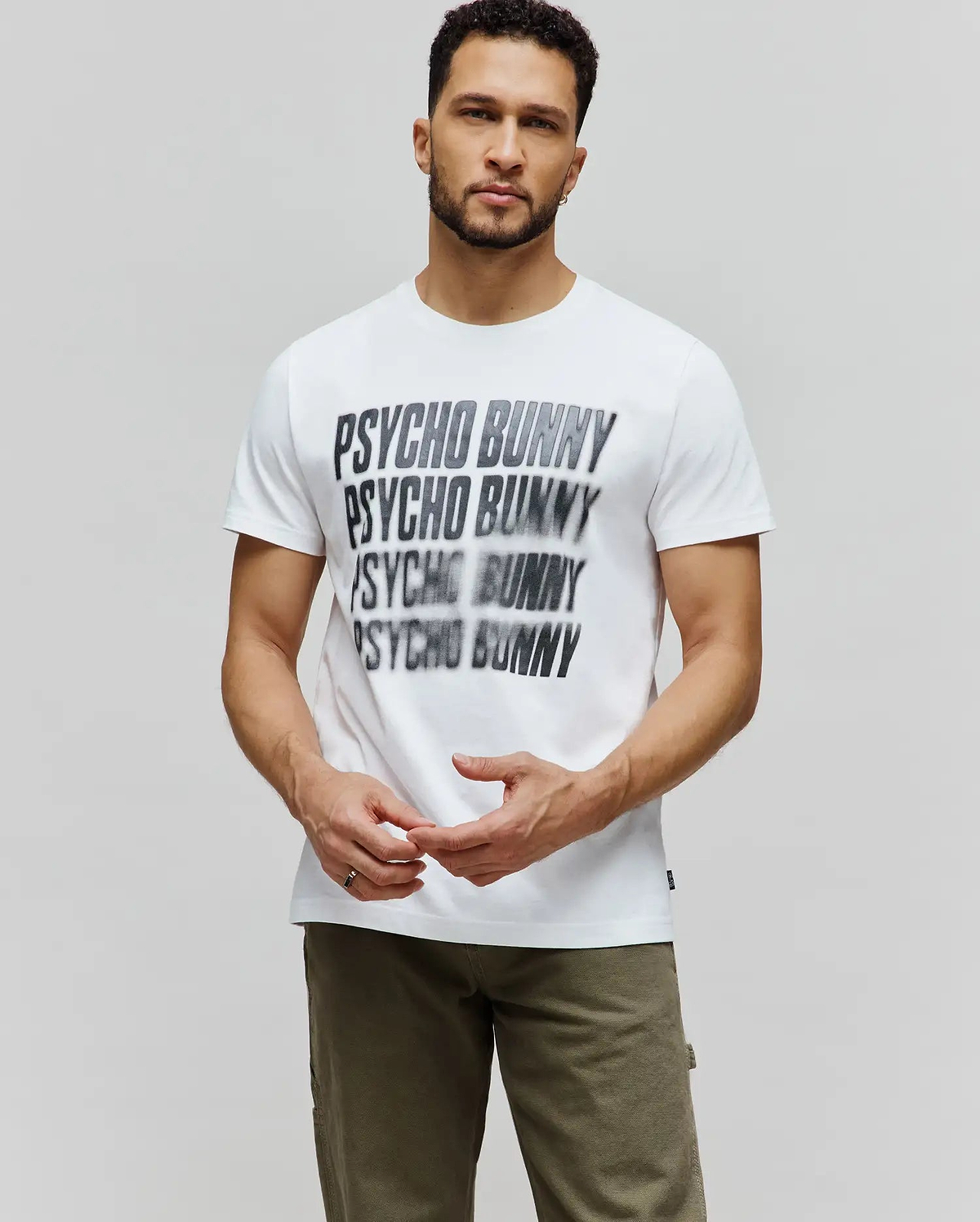 Mens Lawrence Graphic Tee, white classic fit jersey t-shirt with a large, central black and grey blurred PSYCHO BUNNY text graphic repeated down the chest. (2)