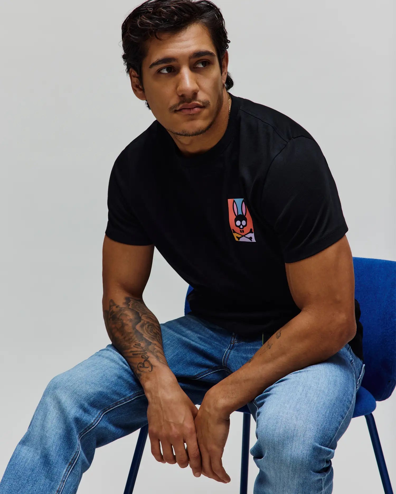 Mens Raphael Back Graphic Tee, a classic fit black jersey t-shirt featuring a small, vibrant multicolor Psycho Bunny skull graphic on the left chest. (4)