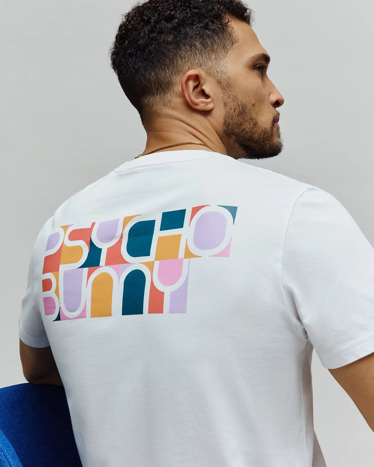 Mens Raphael Back Graphic Tee, a white classic fit jersey t-shirt featuring a large, vibrant, multicolored geometric Psycho Bunny logo graphic on the upper back. (2)