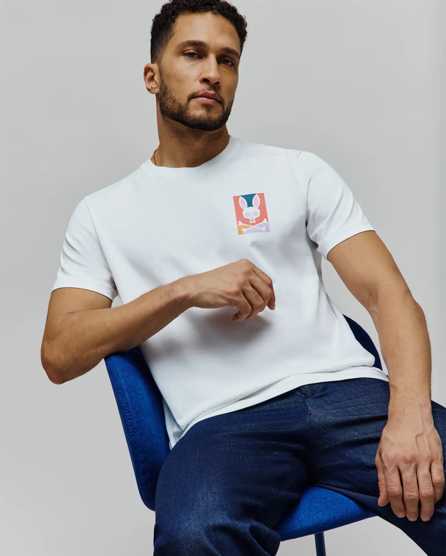 Mens Raphael Back Graphic Tee, a white classic fit jersey t-shirt featuring a small, vibrant Psycho Bunny skull and crossbones graphic on the left chest. (6)