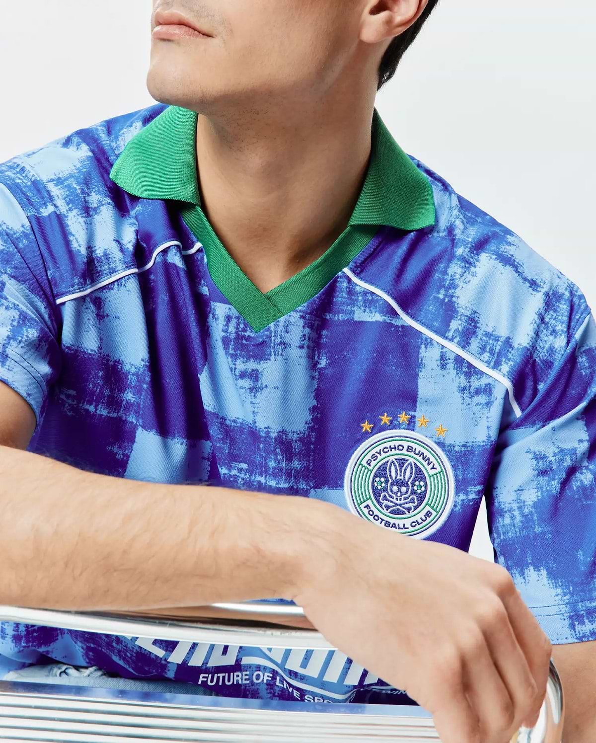 Mens Micah Oversized Soccer Jersey in a distressed blue pattern with a vibrant green ribbed collar, white piping, and a large embroidered Psycho Bunny Football Club patch with gold stars on the right chest. (3)