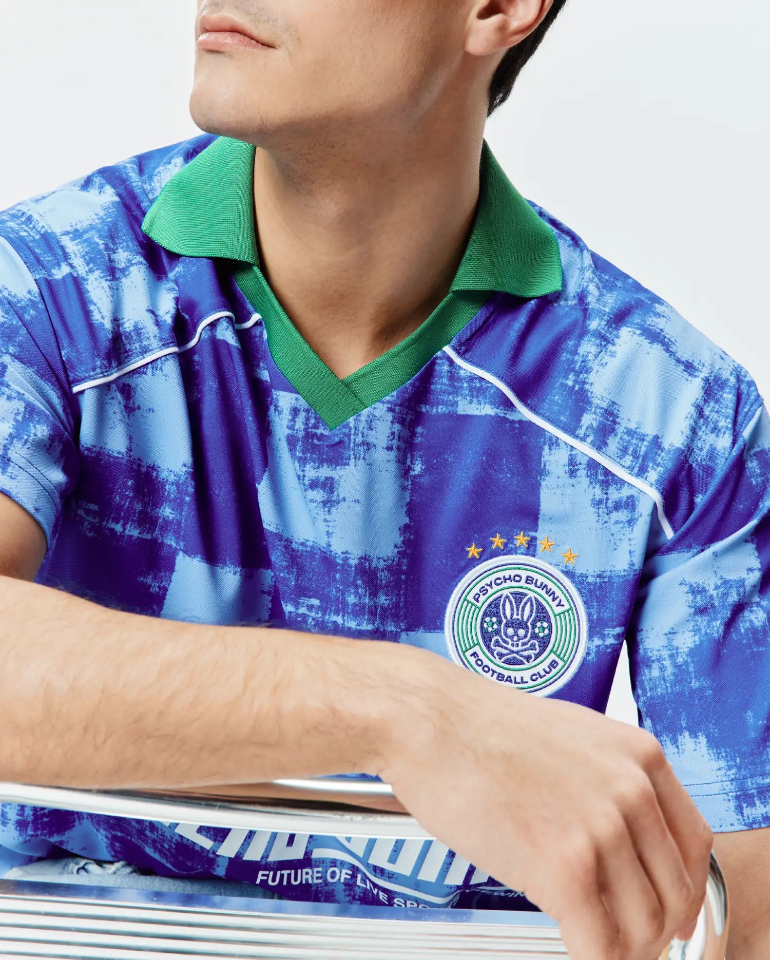 Mens Micah Oversized Soccer Jersey in a distressed blue pattern with a vibrant green ribbed collar, white piping, and a large embroidered Psycho Bunny Football Club patch with gold stars on the right chest. (3)