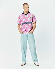 Micah Oversized Soccer Jersey in a bold pink and white distressed checkerboard pattern, featuring a navy V-neck collar, a small circular Psycho Bunny Football Club logo on the left chest, and a large Psycho Bunny text graphic across the chest. (4)