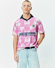 Micah Oversized Soccer Jersey in pink and white distressed checkerboard, with a navy collar, large Psycho Bunny chest text, and a circular Football Club patch featuring the iconic bunny skull logo. (1)