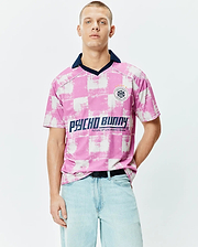 Micah Oversized Soccer Jersey in pink and white distressed checkerboard, with a navy collar, large Psycho Bunny chest text, and a circular Football Club patch featuring the iconic bunny skull logo. (1)