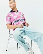 Mens Micah Oversized Soccer Jersey in pink and white distressed checkerboard pattern, featuring a navy V-neck collar, large navy PSYCHO BUNNY text, and a small crest logo on the chest. (3)