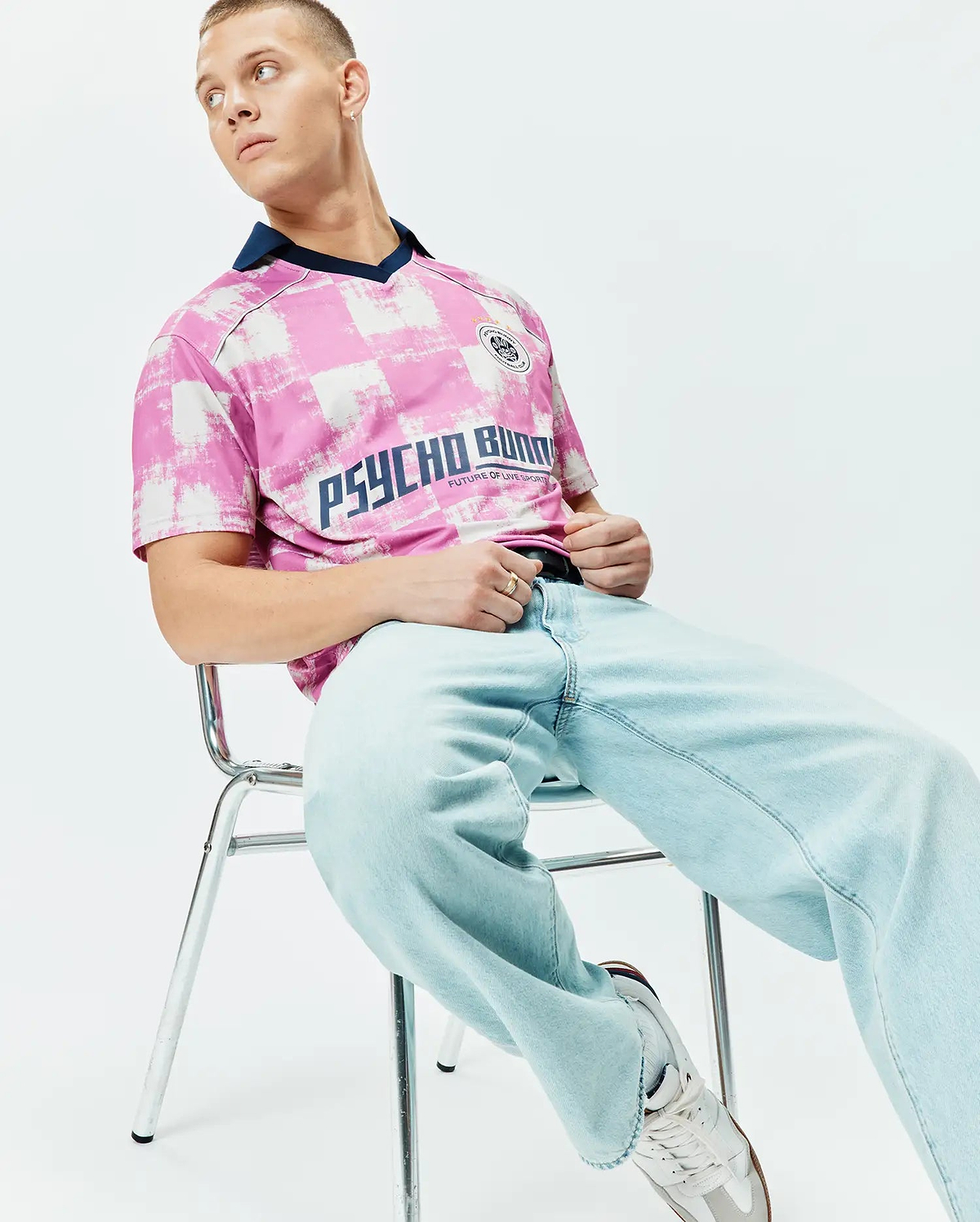 Mens Micah Oversized Soccer Jersey in pink and white distressed checkerboard pattern, featuring a navy V-neck collar, large navy PSYCHO BUNNY text, and a small crest logo on the chest. (3)