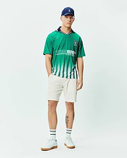 Mens Camden Oversized Soccer Jersey in vibrant green jersey fabric, featuring a navy collar, white fading vertical stripes, a large white PSYCHO BUNNY graphic, and a small embroidered bunny skull logo on the chest. (4)