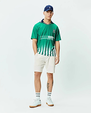 Mens Camden Oversized Soccer Jersey in vibrant green jersey fabric, featuring a navy collar, white fading vertical stripes, a large white PSYCHO BUNNY graphic, and a small embroidered bunny skull logo on the chest. (4)