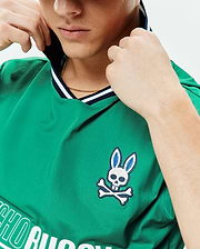 Mens Camden Oversized Soccer Jersey in vibrant green, featuring a navy and white striped V-neck, an embroidered Psycho Bunny skull logo on the left chest, and a large white Psycho Bunny text graphic. (3)