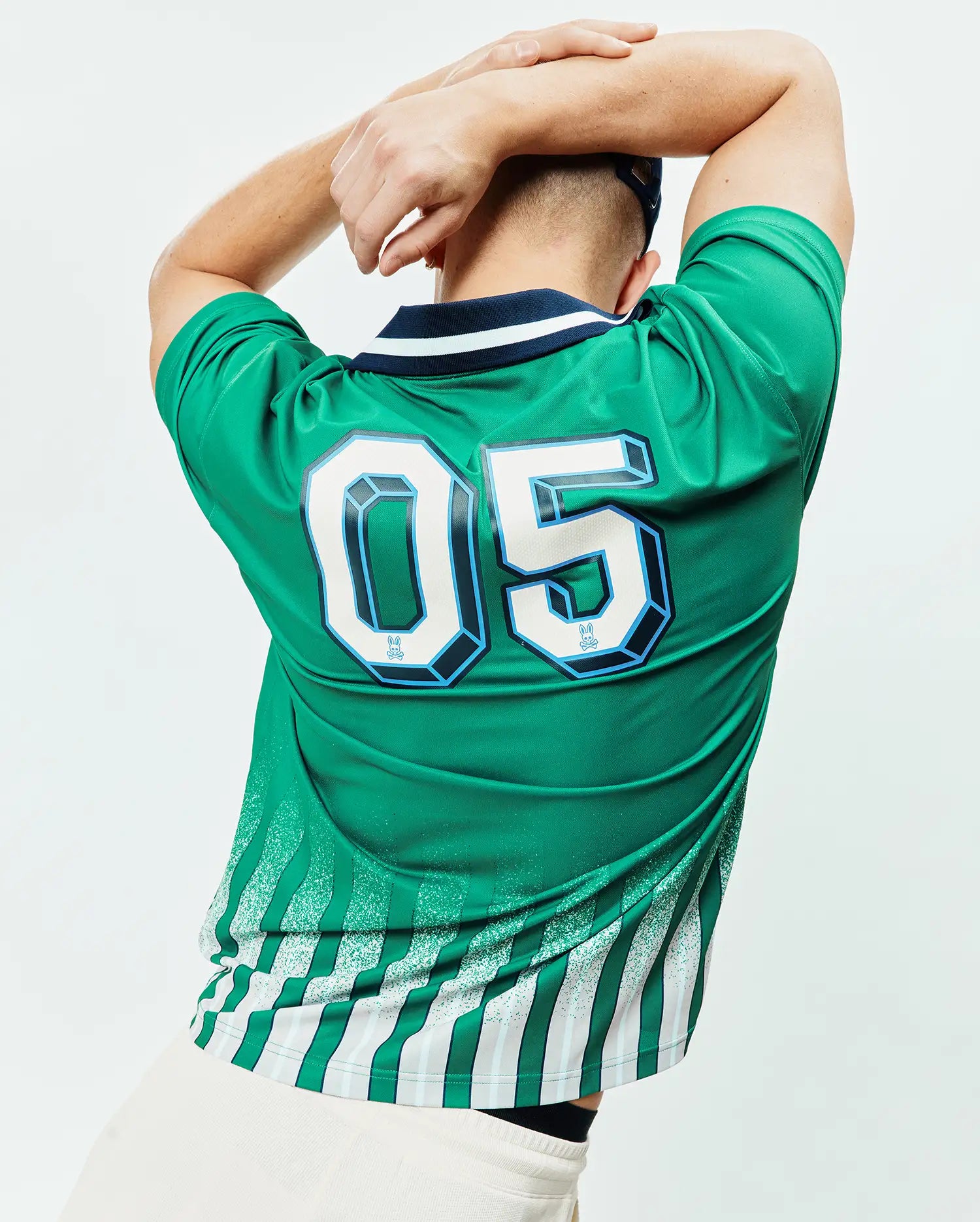 Vibrant green Mens Camden Oversized Soccer Jersey with navy/white ribbed collar. Back features large 3D white/light blue 05 numbers, embedded Psycho Bunny skull logos, and a distressed green/white/grey striped pattern. (2)