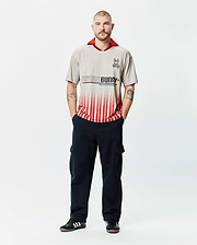Mens Camden Oversized Soccer Jersey in stone grey with a vibrant red collar, featuring a large black Psycho Bunny text logo fading into bold red vertical stripes, and an embroidered bunny skull on the left chest. (4)