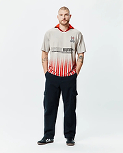 Mens Camden Oversized Soccer Jersey in stone grey with a vibrant red collar, featuring a large black Psycho Bunny text logo fading into bold red vertical stripes, and an embroidered bunny skull on the left chest. (4)