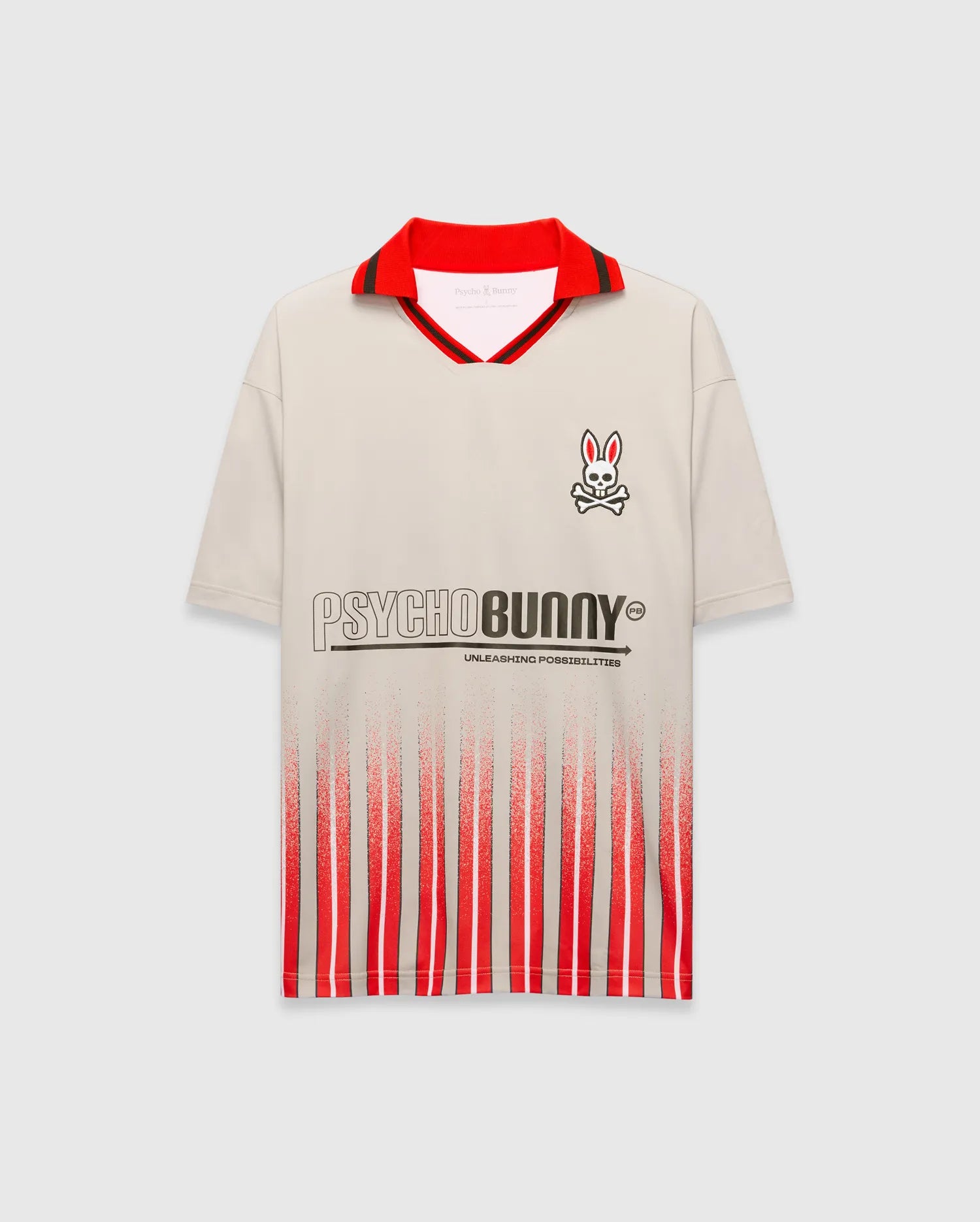 Mens Camden Oversized Soccer Jersey in beige, with a red polo collar, black stripe, small right chest Psycho Bunny skull logo, large PSYCHOBUNNY graphic, and red/black distressed vertical stripes. (5)