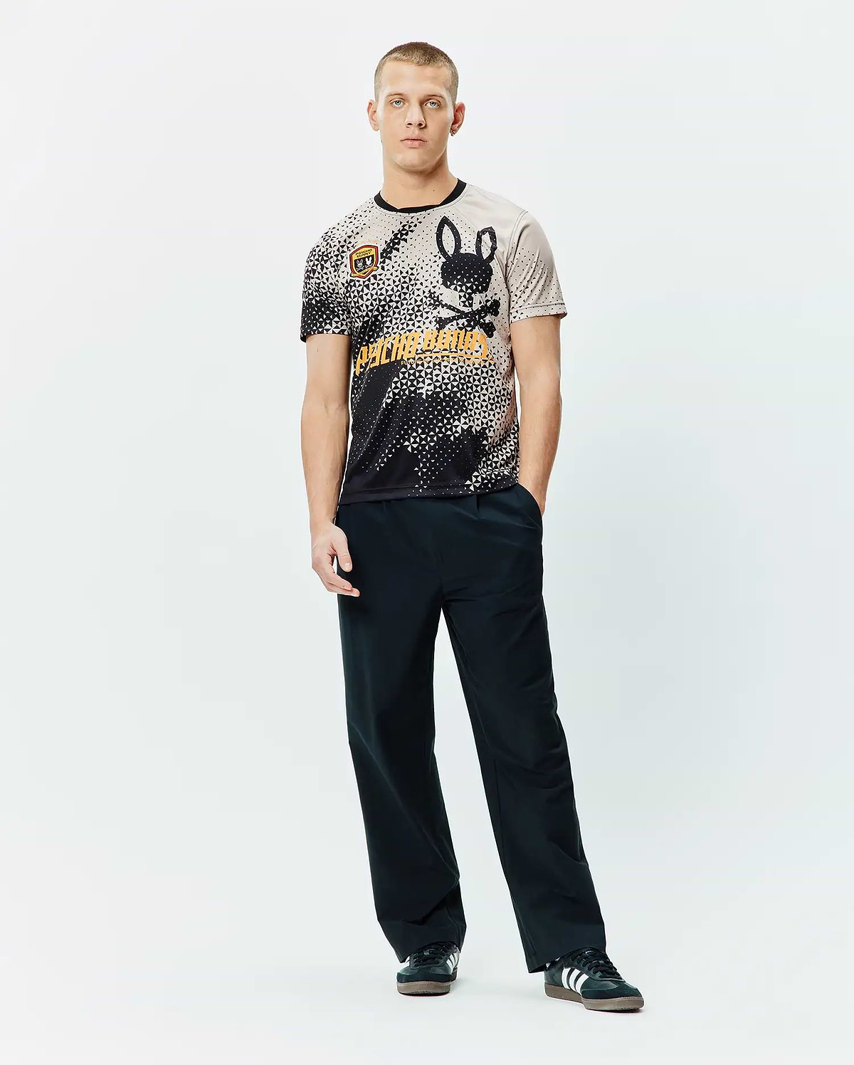 Mens Joshua Soccer Tee featuring a black and beige pixelated gradient, large black bunny skull logo, bold orange Psycho Bunny text, and a small shield patch on a classic fit jersey knit. (4)