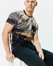 Mens Joshua Soccer Tee, a classic fit black and beige geometric triangle pattern jersey with an embroidered Psycho Bunny Football Club patch, large bunny skull graphic, and bold orange Psycho Bunny text. (3)