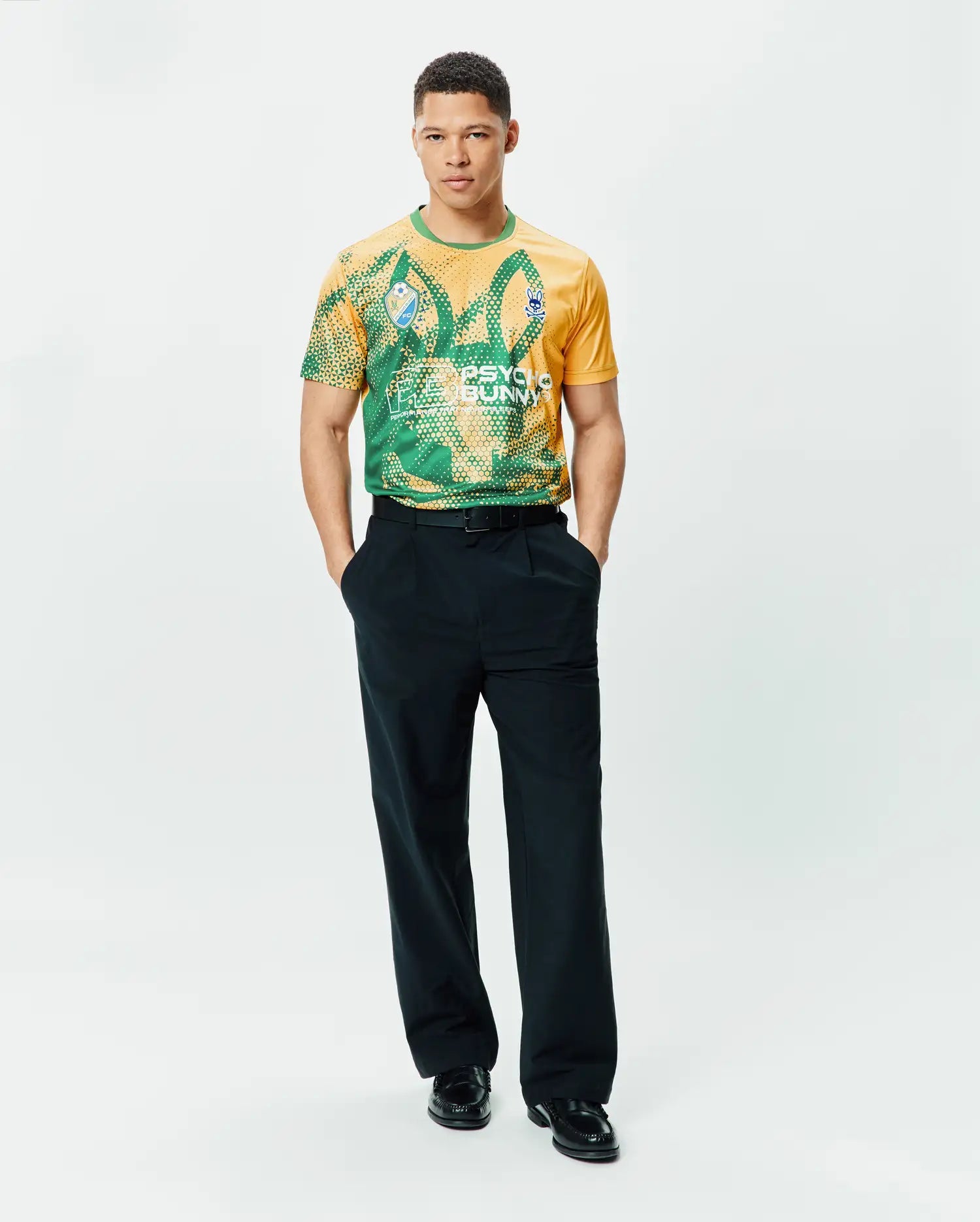 Mens Joshua Soccer Tee in gold and green geometric pattern, featuring a large PSYCHO BUNNY graphic and small blue bunny skull logo on the left chest, classic fit performance jersey. (5)