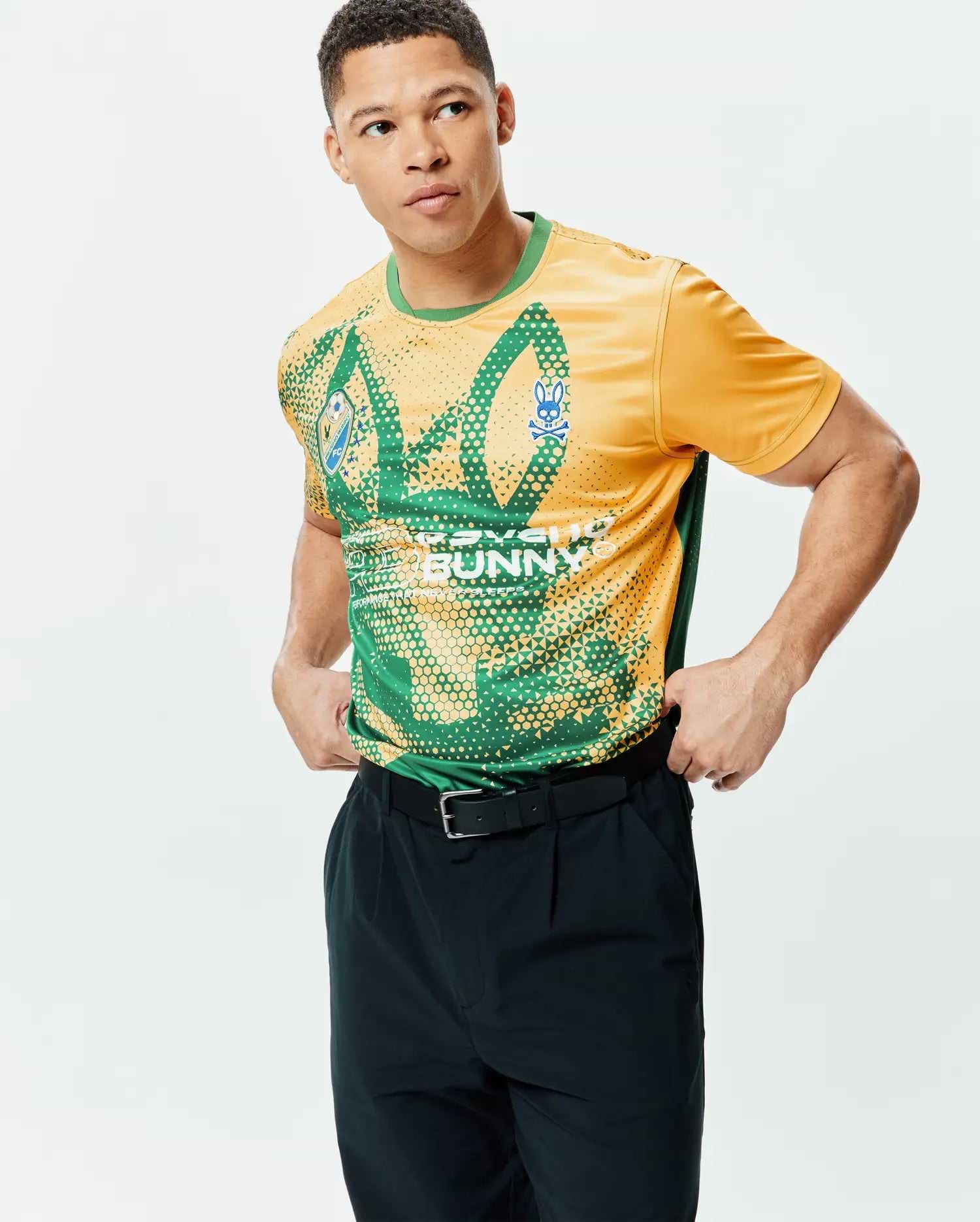 MENS JOSHUA SOCCER TEE in gold and green jersey, featuring an all-over geometric pattern, a blue Psycho Bunny skull logo on the left chest, and large PSYCHO BUNNY text on the front, with a classic fit. (2)
