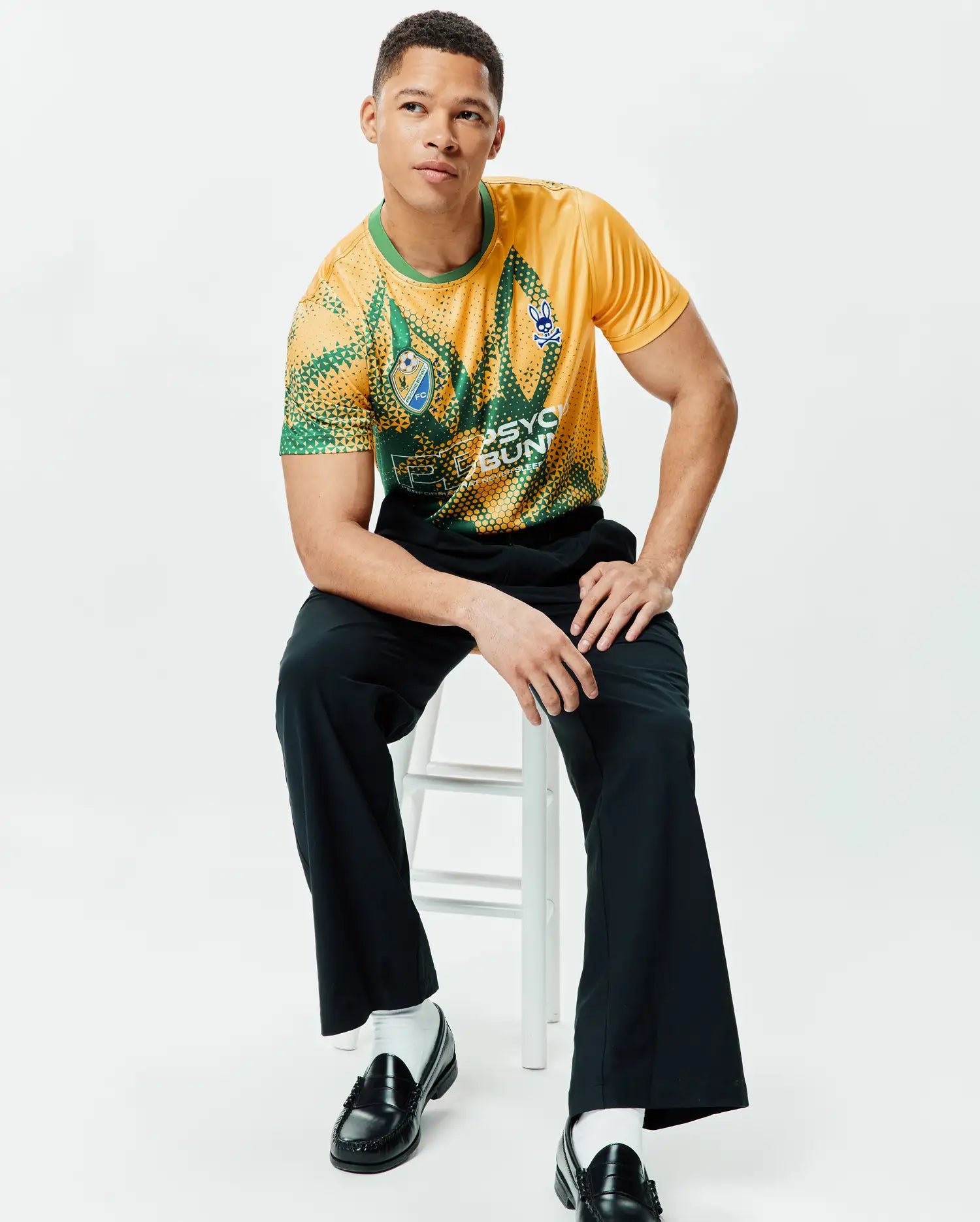 Mens Joshua Soccer Tee in yellow and green geometric dot pattern, featuring a blue Psycho Bunny skull logo on the right chest, an FC logo on the left chest, and large Psycho Bunny text on the front. Classic fit, smooth jersey. (4)