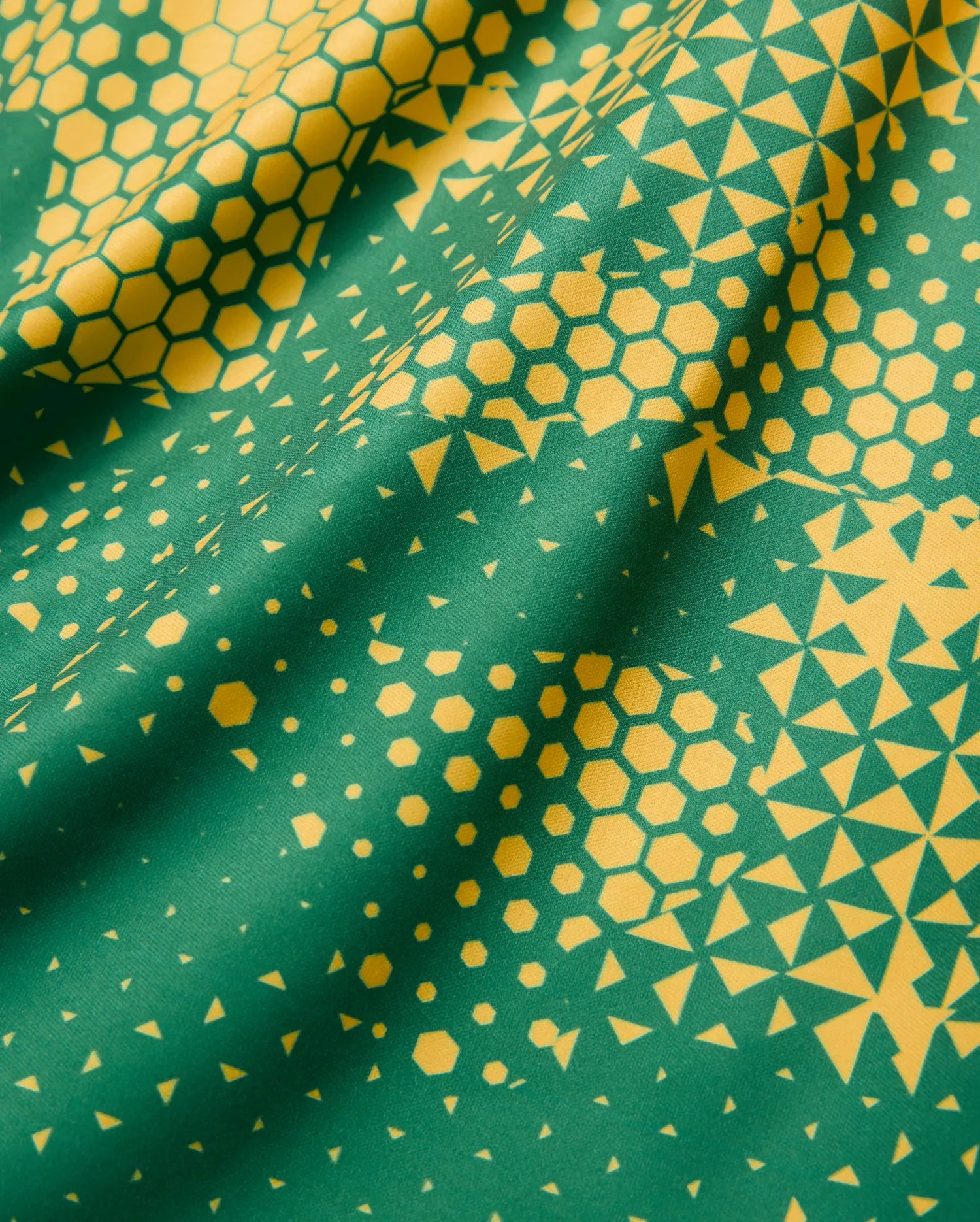 Joshua Soccer Tee featuring a bold green base with a vibrant yellow geometric pattern, transitioning from dense hexagons to scattered triangles on a smooth performance fabric. (7)